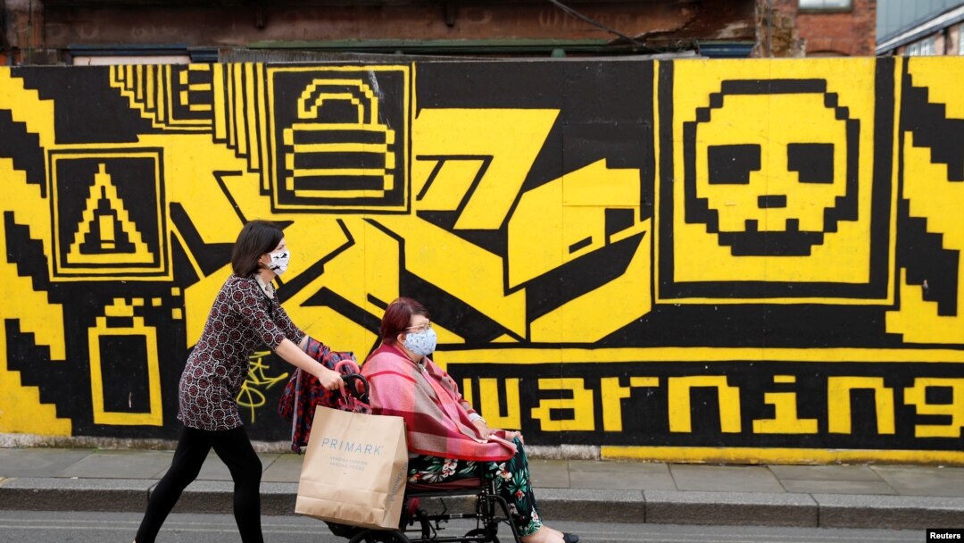 People wearing protective face masks walk down the street, as the city and surrounding areas face local restrictions in an effort to avoid a local lockdown being forced upon the region, in Manchester, Britain, Aug. 3, 2020.