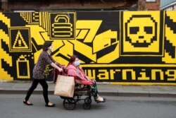 People wearing protective face masks walk down the street, as the city and surrounding areas face local restrictions in an effort to avoid a local lockdown being forced upon the region, in Manchester, Britain, Aug. 3, 2020,