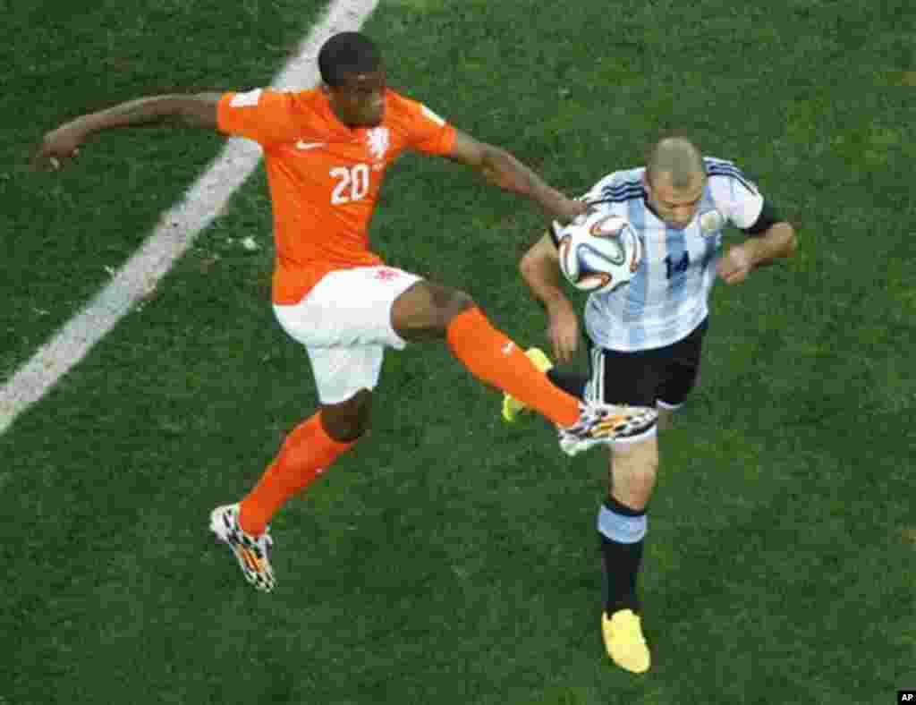 Netherlands' Georginio Wijnaldum, left, and Argentina's Javier Mascherano go for the ball during the World Cup semifinal soccer match between the Netherlands and Argentina at the Itaquerao Stadium in Sao Paulo, Brazil, Wednesday, July 9, 2014. (AP Photo/F