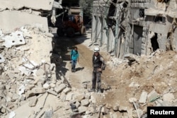 Civil defense members and men inspect a site damaged after an airstrike in the besieged rebel-held al-Qaterji neighborhood of Aleppo, Syria, Oct. 11, 2016.