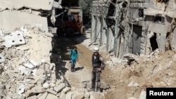 FILE - Civil defense members and men inspect a site damaged after an airstrike in the besieged rebel-held al-Qaterji neighborhood of Aleppo, Syria, Oct. 11, 2016.