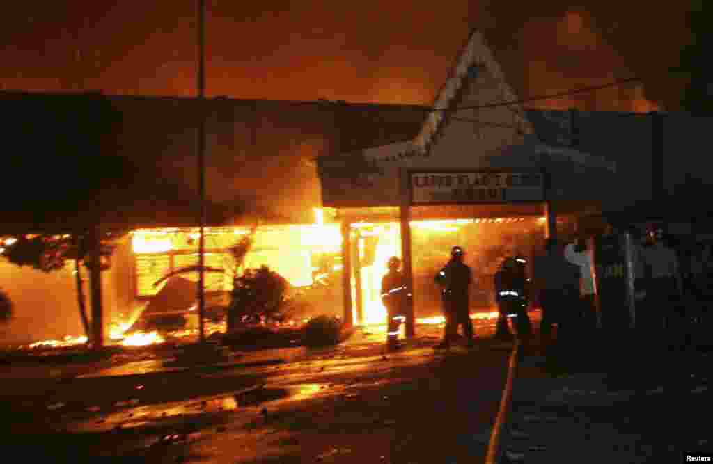 Firefighters and police officers stand outside Tanjung Gusta prison, which was set ablaze by inmates after a riot broke out, in Medan, North Sumatra province, July 11, 2013.&nbsp;