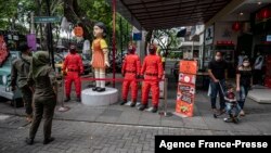 People walk past statues featuring characters from the Netflix series Squid Game at a food court to attract visitors in Surabaya on Oct. 21, 2021.