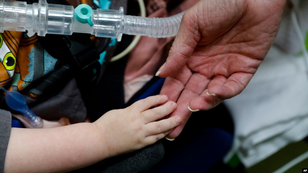 Registered nurse Coleen McMahon, a specialist in pediatric program development, touches the hand of a patient at a pediatric medical facility in Las Vegas, Sept. 10, 2016.