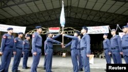 Newly graduated airmen hand over their flag to the next class during a graduation ceremony at Al-Hurria airport in Kirkuk, 250 km (155 miles) north of Baghdad, Feb.1, 2010. 