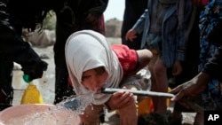 Seorang anak perempuan meminum air dari sumur yang diduga sudah tercemar bakteri kolera di pinggiran kota Sanaa, Yaman. (Foto:dok)