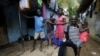 FILE - Laboratory technician Mohamed SK Sesay, who survived Ebola but saw many of his colleagues die and now has joint and muscle pains and loss of sight, holds the child of one of his work colleagues who died of the disease, in Kenema, Sierra Leone, Aug. 9, 2015.