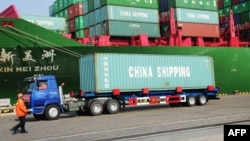 FILE - A truck transporting a container leaves the port of Qingdao, in northeast China's Liaoning province.