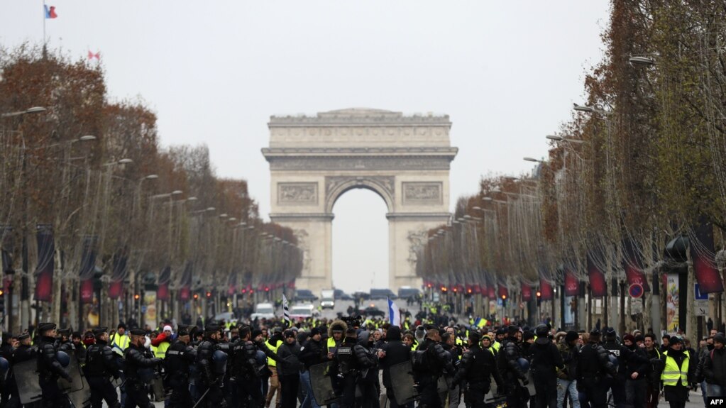 2018年12月15日，在法国巴黎的香榭丽舍大街，防暴警察站在身穿黄色马甲的抗议者面前，这些抗议者抗议高税收导致的生活成本上涨。（法新社）(photo:VOA)