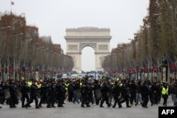 French riot police take position in front of protesters wearing yellow vests (gilets jaunes) demonstrating against rising costs of living they blame on high taxes on the Champs-Elysees in Paris, Dec. 15, 2018.