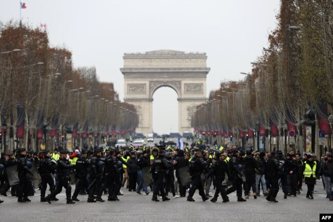 French riot police take position in front of protesters wearing yellow vests (gilets jaunes) demonstrating against rising costs of living they blame on high taxes on the Champs-Elysees in Paris, Dec. 15, 2018.