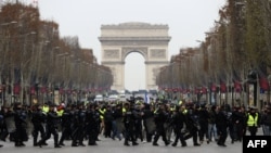 French riot police take position in front of protesters wearing yellow vests (gilets jaunes) demonstrating against rising costs of living they blame on high taxes on the Champs-Elysees in Paris, Dec. 15, 2018.