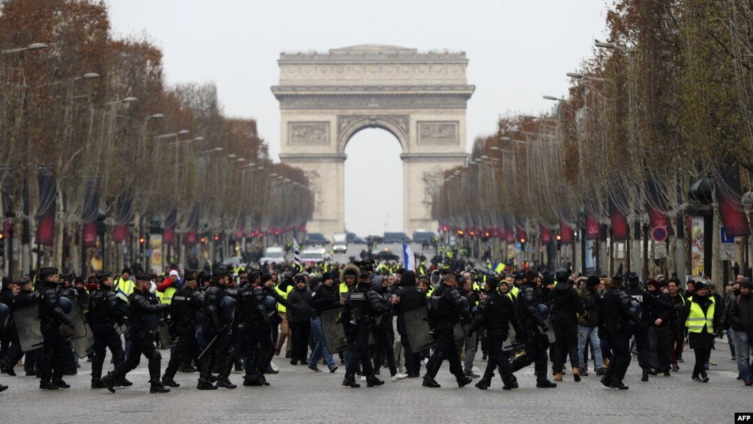 Polisi anti huru-hara Perancis menghadang para demonstran berjaket kuning (gilets jaunes) yang berunjuk rasa memprotes kenaikan harga BBM di Champs-Elysees, Paris, 15 Desember 2018. (Foto: dok).
