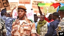 A national guard soldier walks by demonstrators at Bamako airport, Mali, March 29, 2012. (N. Palus / VOA)