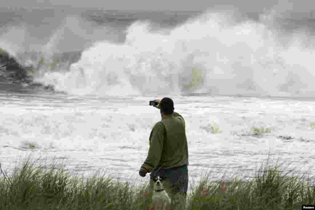 A man with a small dog takes a photo of the storm waves from Hurricane Sandy in Ocean City, New Jersey, October 28, 2012.