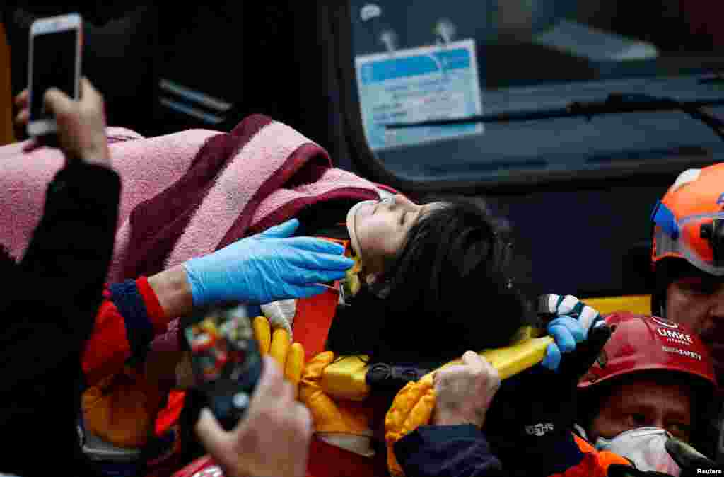 Rescuers carry a girl on a stretcher at the site of a collapsed residential building in the Kartal district, Istanbul, Turkey.