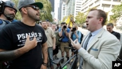 Joey Gibson, left, founder of the Patriot Prayer group, argues with a bystander at right as Gibson's group marched following a rally supporting gun rights, Aug. 18, 2018, at City Hall in Seattle.