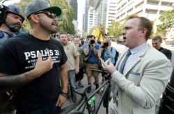 FILE - Joey Gibson, left, founder of the Patriot Prayer group, argues with a bystander at right as Gibson's group marched following a rally supporting gun rights, Aug. 18, 2018, at City Hall in Seattle.