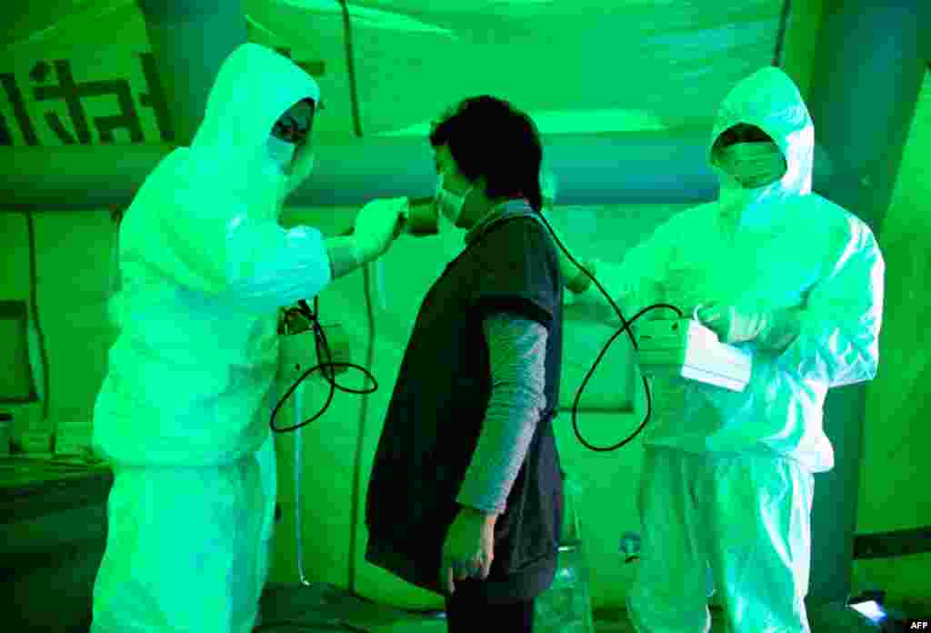 Medical staff use a Geiger counter to screen a woman for radiation exposure after she evacuated from an area within 20km (12.4 miles) radius of the Fukushima Daiichi nuclear plant. (Reuters)