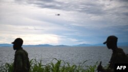 A United Nations helicopter flies over the Lake Kivu as M23 rebels walk along the shore in the city of Goma, east of the Democratic Republic of the Congo. Taken Nov.20, 2012. 