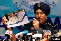 FILE - Commissioner Amar Singh, Malaysia's Federal Commercial Crime Investigation Department (CCID) director, displays a photo of items from a raid during a news conference in Kuala Lumpur, June 27, 2018.