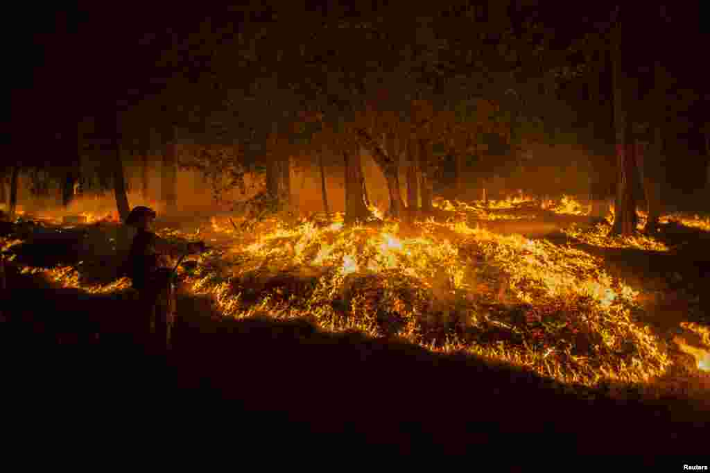A firefighter battling the King Fire sprays water on a backfire in Fresh Pond, California, USA, Sept. 17, 2014. Fire crews in California&#39;s rugged Sierra Nevada battled to gain the upper hand against a blaze that threatened at least 2,000 homes and has displaced hundreds of residents as flames roared for a fifth day through dry timber and brush west of Lake Tahoe. 