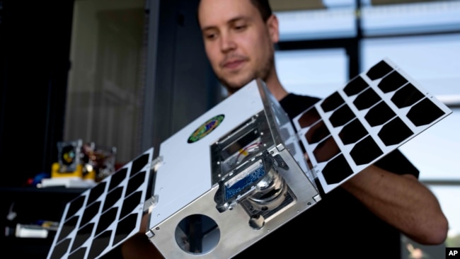 An employee of the German startup OroraTech lifts a satellite enclosure in Munich, Germany, Sept. 13, 2023. The Munich-based company analyzes satellite images with artificial intelligence to identify those flareups that have the potential to spawn devastating megafires.