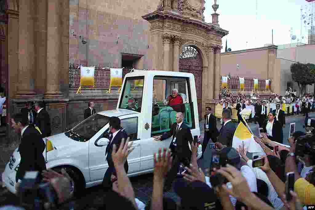 Pope Benedict XVI waves to faithful from his popemobil as arrives for a vespers with bishops of Mexico and the American continent at the cathedral in Leon, Mexico, March 25, 2012. (AP)