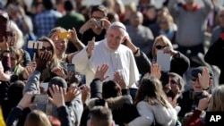 Le pape François salue la foule à son arrivée pour son audience générale hebdomadaire à Place Saint-Pierre, au Vatican, le mercredi 1er mars 2017.