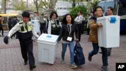 韩国全国选举委员会官员与警官抬着国会选举的票箱到达首尔的点票办公室 (2016年4月13日)