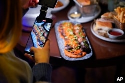 ILUSTRASI - Seorang kreator konten tengah mengambil video di sebuah restoran di Charlotte, North Carolina, 14 Maret 2024. (Erik Verduzco/AP)