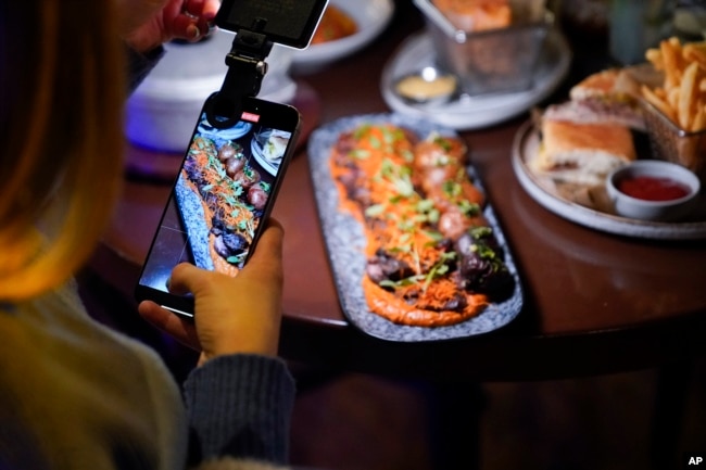 ILUSTRASI - Seorang kreator konten tengah mengambil video di sebuah restoran di Charlotte, North Carolina, 14 Maret 2024. (Erik Verduzco/AP)