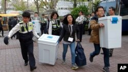 South Korean National Election Commission officials and police officers carry boxes containing ballots for parliamentary election as they arrive at a ballot counting office in Seoul, South Korea, April 13, 2016. 