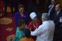 U.S. Representative Ilhan Omar is embraced by Ghana's former president, Jerry John Rawlings, at Ghana's parliament, July 31, 2019. (S. Knott/VOA)