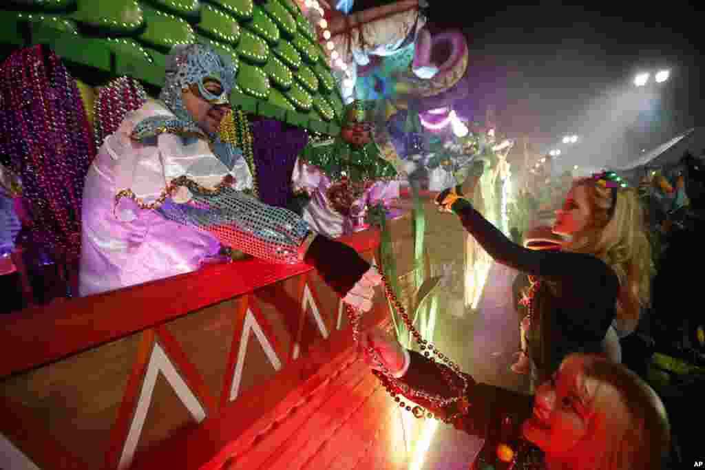 Participantes en las carrozas flotantes regalan collares a la multitud mientras el Krewe of Orpheus avanza en Nueva Orleáns, el lunes 12 de febrero de 2018. Decenas de miles de juerguistas llenan las calles de Nueva Orleans para desfiles y diversión mientras el Mardi Gras cierra la temporada de Carnaval en una ciudad con una celebración propia, su 300 aniversario. (AP Photo / Gerald Herbert)