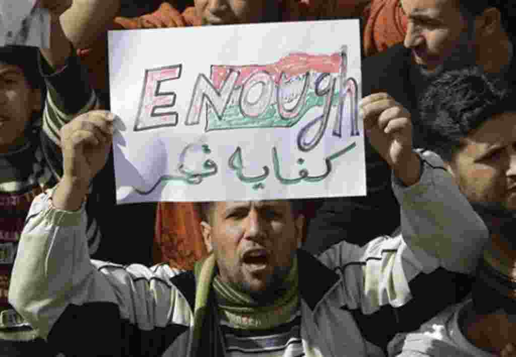 A Libyan protester holds up a sign against Libyan Leader Moammar Gadhafi during a demonstration, in Tobruk, Libya, February 23, 2011.