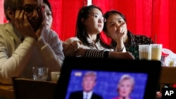 Chinese students chat as they watch a live broadcasting of the presidential debate between Democratic presidential nominee Hillary Clinton and Republican presidential nominee Donald Trump, at a cafe in Beijing, Sept. 27, 2016.