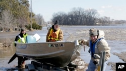 Tom Wilke, center, his son Chad, right, and Nick Kenny, load a boat out of the swollen waters of the North Fork of the Elkhorn River after checking on the Witke's flooded property, in Norfolk, Neb., Friday, March 15, 2019.