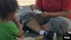 A Honduran woman and her 18-month-old daughter share lunch hours after being dropped off in Nuevo Laredo, Mexico, under the Migrant Protection Protocols, Aug. 8, 2019. (V. Macchi/VOA)