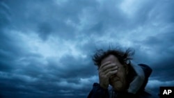 Russ Lewis covers his eyes from a gust of wind and a blast of sand as Hurricane Florence approaches Myrtle Beach, S.C., Sept. 14, 2018.