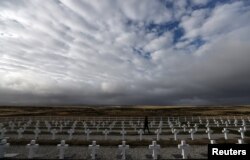 FILE - A woman visits Darwin cemetery, where Argentine soldiers who died during the Falklands war are buried, in the Falkland Islands, May 16, 2018.