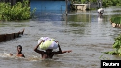 People wade through a flood with their belongings after their houses were submerged in the Amassoma community in Bayelsa state, Nigeria, October 6, 2012. 