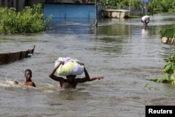 People wade through a flood with their belongings after their houses were submerged in the Amassoma community in Bayelsa state, Nigeria, October 6, 2012.