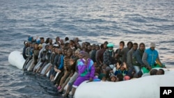 In this Feb. 3, 2017 file photo, migrants and refugees wait to be helped by members of the Spanish NGO Proactiva Open Arms, as they crowd aboard a rubber boat sailing out of control in the Mediterranean Sea about 21 miles north of Sabratha, Libya.