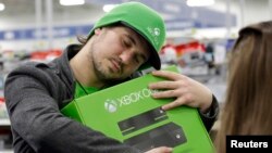 Emanuel Jumatate, from Chicago, hugs his new Xbox One after he purchased it at a Best Buy, Nov. 22, 2013, in Evanston, Illinois. 