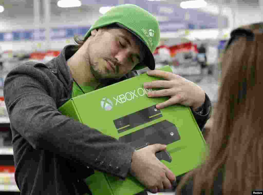 Emanuel Jumatate, from Chicago, hugs his new Xbox One after he purchased it in Evanston, Illinois. Microsoft is billing the Xbox One as an all-in-one entertainment system rather than just a gaming console.
