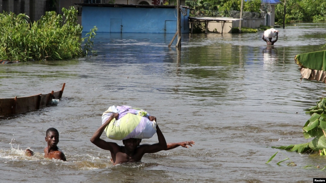 People wade through a flood with their belongings after their houses were submerged in the Amassoma community in Bayelsa state, Nigeria, October 6, 2012. 
