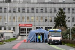 FILE - Paramedics stand by a tent that was set up outside the emergency ward of the Cremona hospital, northern Italy, Feb. 29, 2020.