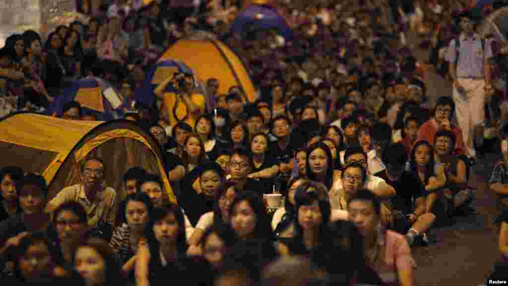 Para demonstran pro-demokrasi menonton pembicaraan formal antara para pemimpin protes mahasiswa dan pejabat pemerintah dari layar video dekat kantor pusat pemerintahan di Hong Kong (21/10). (Reuters/Carlos Barria) 