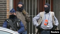 Masked Belgian police secure the entrance to a building in Anderlecht while colleagues carry out a serach in an apartment following Tuesday's bomb attacks in Brussels, Belgium, March 23, 2016. 